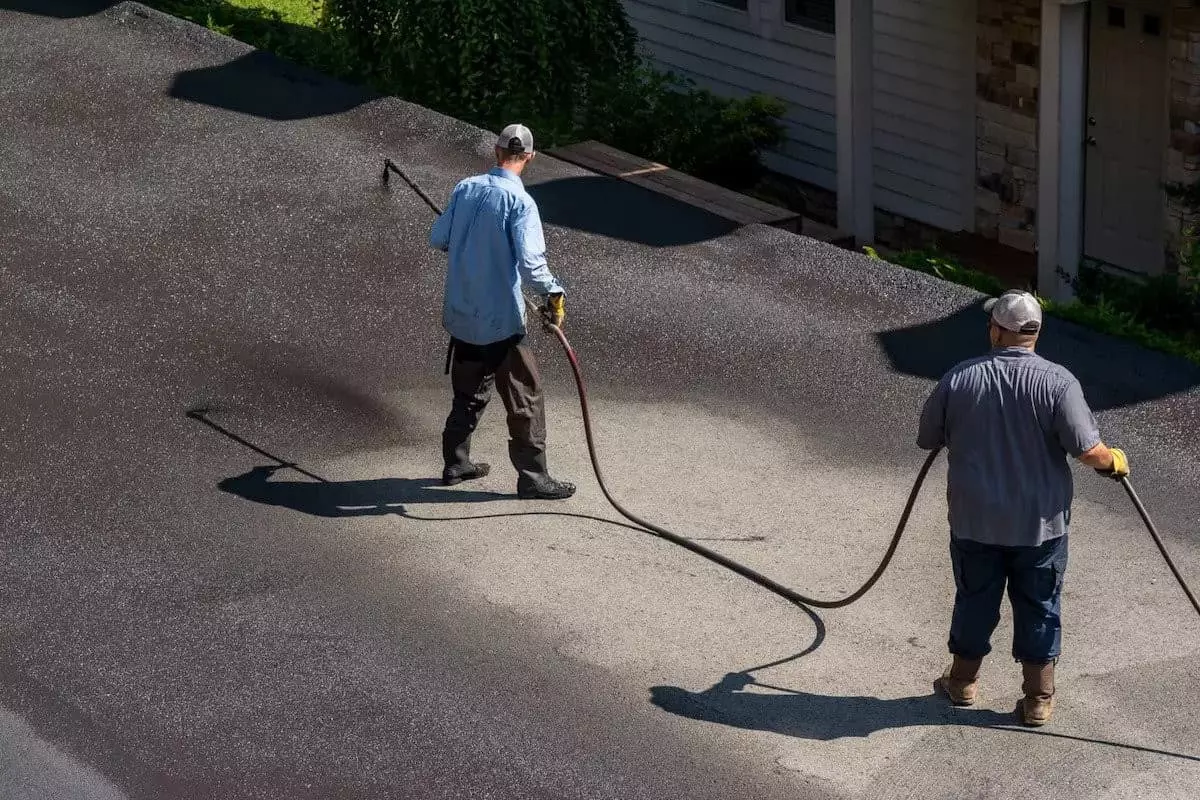 Workers applying sealcoating to a parking lot
